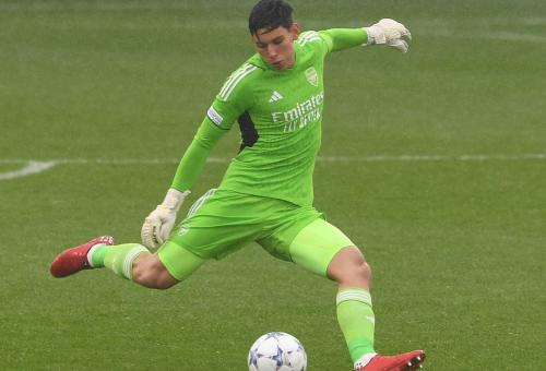 Running footballer in green kit about to kick a football